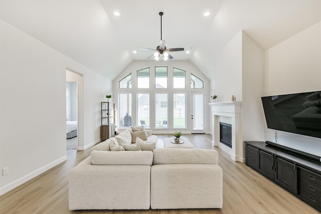 living room with recessed lighting, a ceiling fan, a glass covered fireplace, and light wood-style flooring