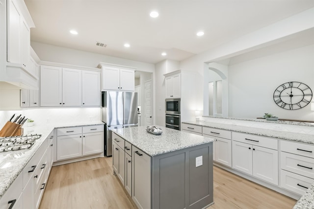kitchen featuring light wood finished floors, a center island, white cabinets, and appliances with stainless steel finishes