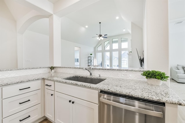 kitchen featuring light stone counters, backsplash, stainless steel dishwasher, a sink, and ceiling fan