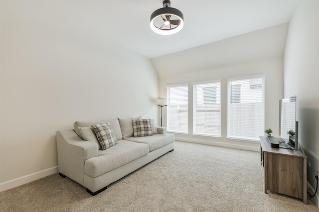 living area with lofted ceiling, light carpet, and baseboards