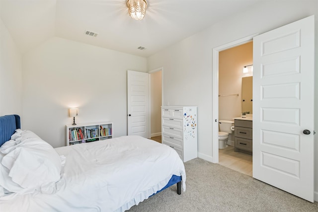 bedroom featuring vaulted ceiling, visible vents, light carpet, and ensuite bathroom