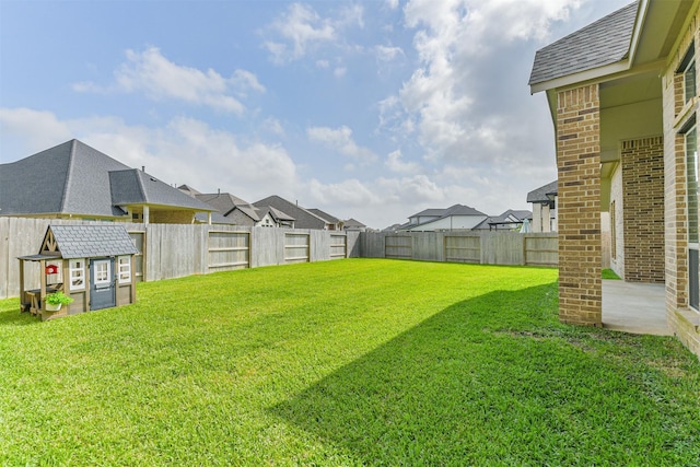 view of yard featuring a residential view, an outbuilding, a shed, and a fenced backyard