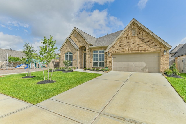 view of front of house featuring a playground, concrete driveway, brick siding, a garage, and a front yard