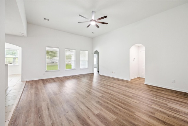 22702 Crate Falls Dr, Hockley, TX 77447 - unfurnished living room featuring arched walkways, ceiling fan, visible vents, and high vaulted ceiling