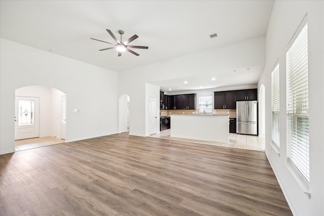 22702 Crate Falls Dr, Hockley, TX 77447 - unfurnished living room with visible vents, arched walkways, light wood finished floors, and a ceiling fan