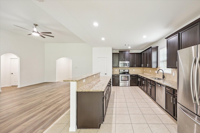 22702 Crate Falls Dr, Hockley, TX 77447 - kitchen featuring a ceiling fan, a kitchen island, tasteful backsplash, arched walkways, and stainless steel appliances
