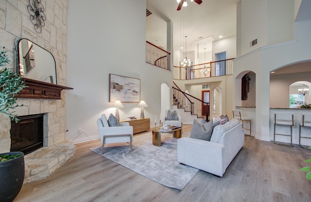 1840 Leela Springs Dr, Conroe, TX 77304 - living room with a high ceiling, wood finished floors, arched walkways, stairs, and ceiling fan with notable chandelier
