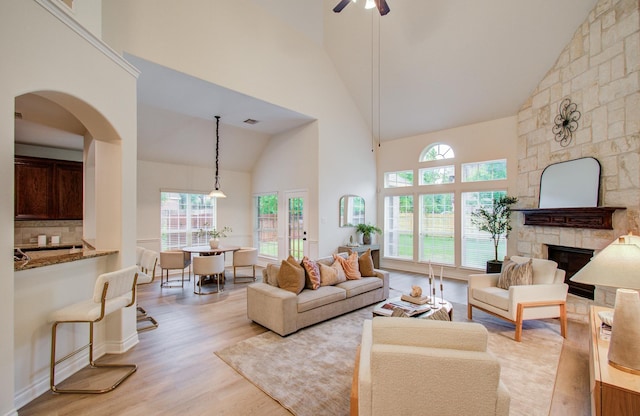 1840 Leela Springs Dr, Conroe, TX 77304 - living room with high vaulted ceiling, a healthy amount of sunlight, a stone fireplace, and light wood-style flooring