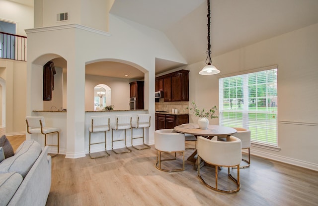 1840 Leela Springs Dr, Conroe, TX 77304 - dining room with arched walkways, visible vents, baseboards, light wood-style floors, and a high ceiling
