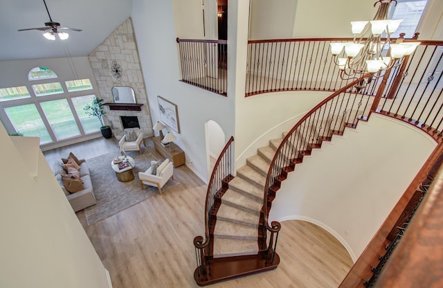 1840 Leela Springs Dr, Conroe, TX 77304 - living area with high vaulted ceiling, stairs, a stone fireplace, wood finished floors, and ceiling fan with notable chandelier