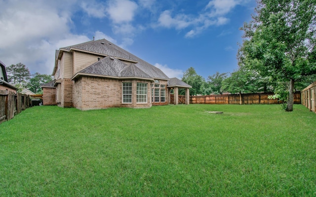 1840 Leela Springs Dr, Conroe, TX 77304 - rear view of house featuring a fenced backyard, a yard, roof with shingles, a gazebo, and brick siding