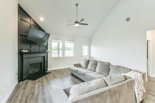living area featuring ceiling fan, light wood finished floors, a fireplace, baseboards, and visible vents