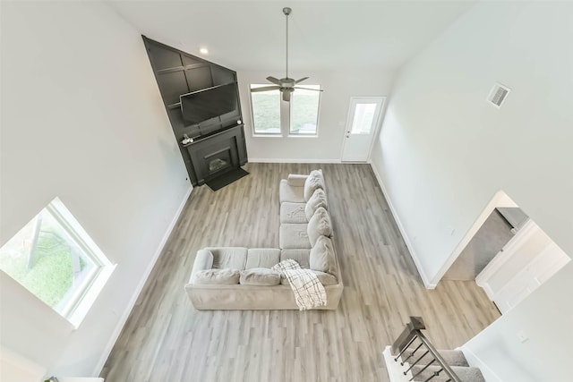 living room with wood finished floors, visible vents, baseboards, a fireplace, and ceiling fan