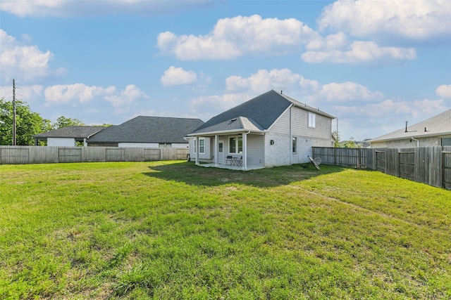 rear view of house featuring a fenced backyard, a yard, and a patio