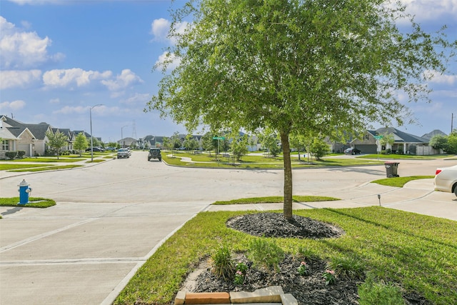 view of road featuring street lights, sidewalks, and a residential view