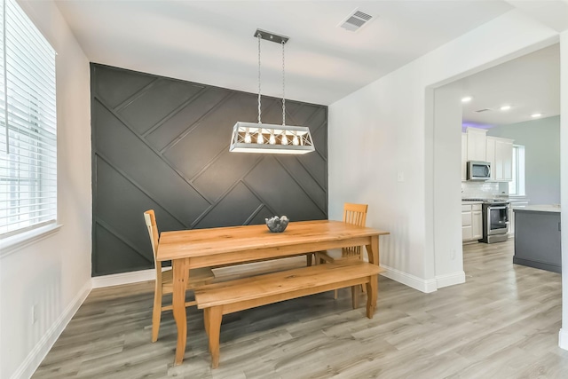 dining space with baseboards, a wealth of natural light, visible vents, and light wood-type flooring