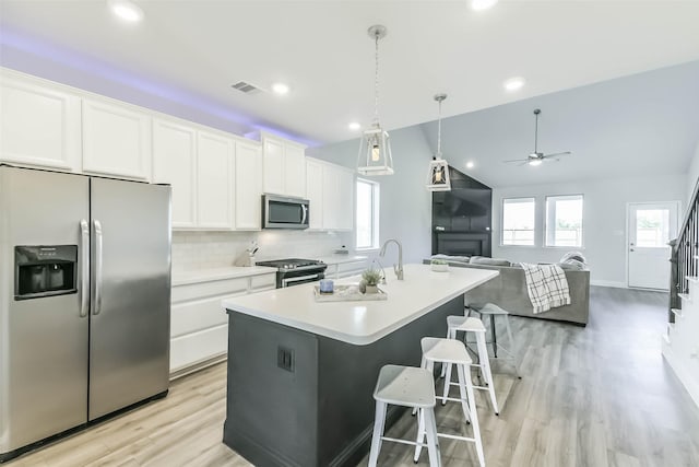 20002 Roan Ardennes Ln, Tomball, TX 77377 - kitchen featuring stainless steel appliances, white cabinetry, light wood-style flooring, a kitchen island with sink, and ceiling fan
