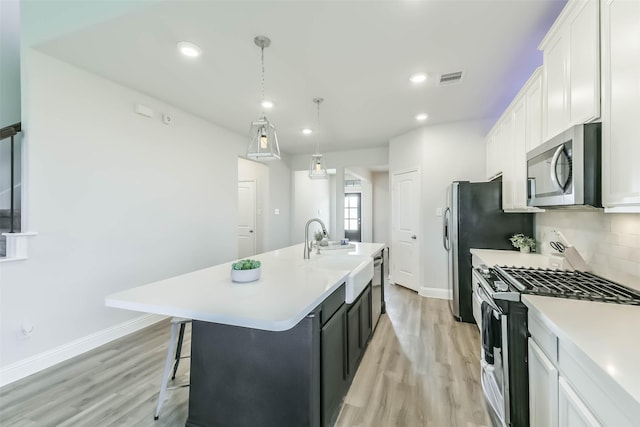 20002 Roan Ardennes Ln, Tomball, TX 77377 - kitchen with appliances with stainless steel finishes, light wood-style flooring, a kitchen island with sink, a sink, and recessed lighting