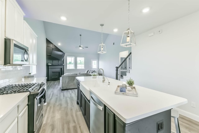 20002 Roan Ardennes Ln, Tomball, TX 77377 - kitchen with appliances with stainless steel finishes, a sink, a fireplace, light wood-style floors, and a ceiling fan