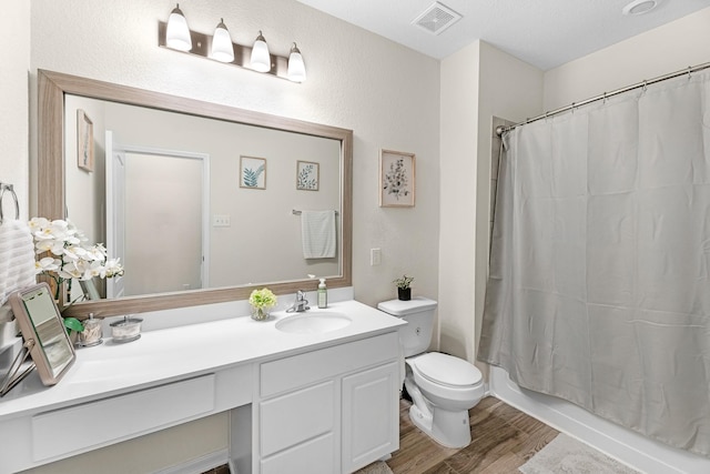 full bathroom featuring wood finished floors, vanity, shower / tub combo, toilet, and visible vents