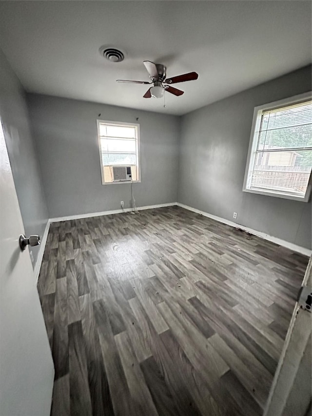 empty room featuring a ceiling fan, wood finished floors, cooling unit, baseboards, and visible vents