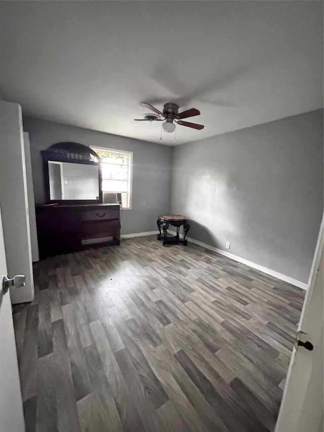 unfurnished bedroom with baseboards, wood finished floors, and ceiling fan