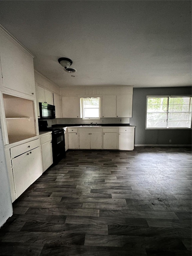 kitchen with white cabinets, dark countertops, dark wood-type flooring, and black appliances