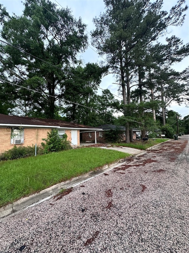 view of front of home with gravel driveway, a carport, and a front yard