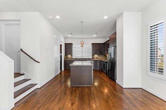 kitchen featuring a healthy amount of sunlight, appliances with stainless steel finishes, a kitchen island, and dark brown cabinets