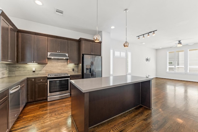 kitchen with visible vents, dark brown cabinets, under cabinet range hood, backsplash, and stainless steel appliances