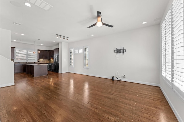 unfurnished living room with baseboards, ceiling fan, and dark wood-type flooring