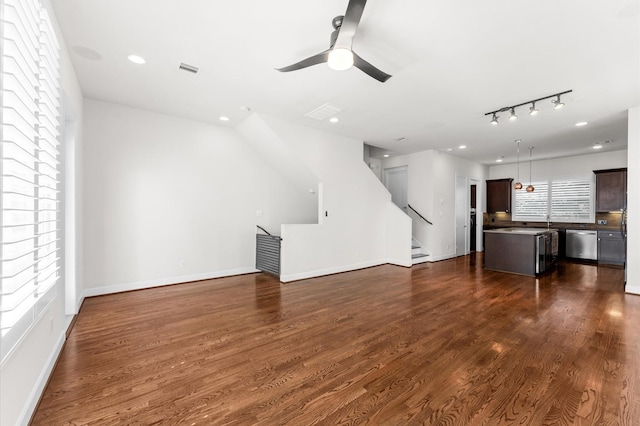 unfurnished living room featuring baseboards, stairs, dark wood-type flooring, and ceiling fan