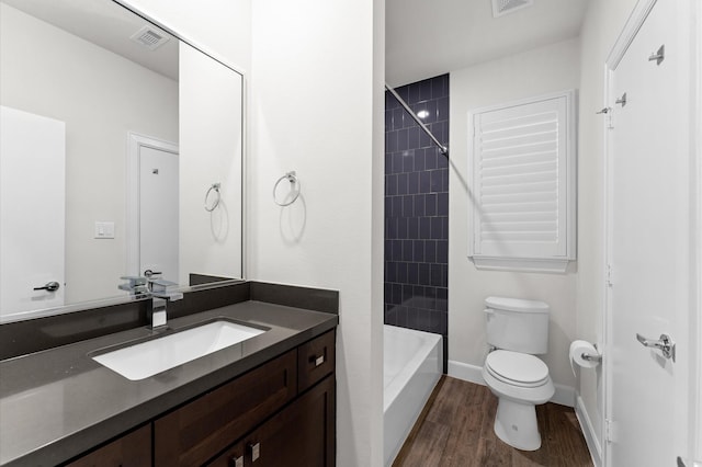 bathroom featuring vanity, toilet, wood finished floors, shower / bathing tub combination, and visible vents