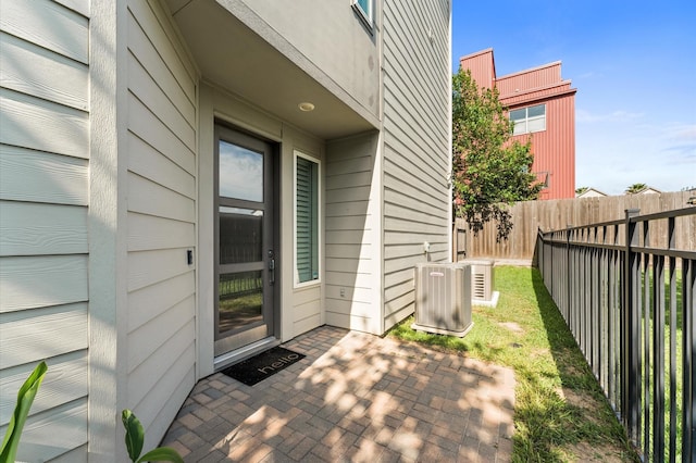 doorway to property with fence, a patio, and central AC unit