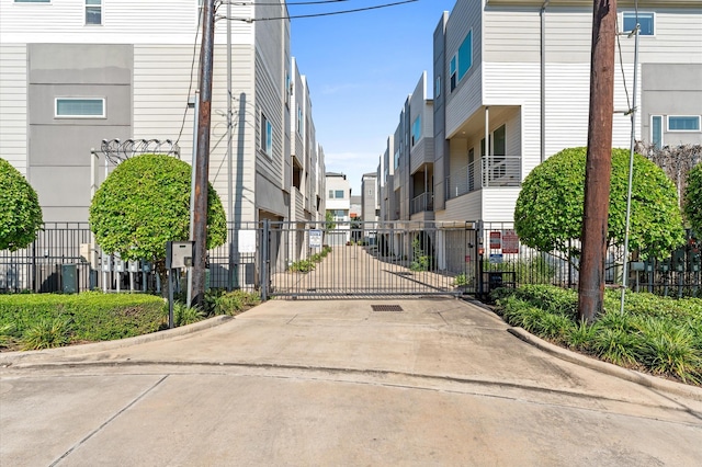 view of road featuring a residential view, a gate, and curbs