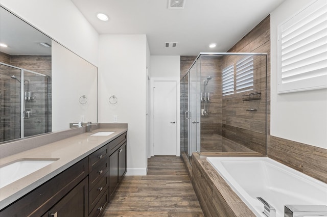 312 Eado Park Cir, Houston, TX 77020 - full bath with double vanity, a stall shower, a bath, recessed lighting, and wood finished floors