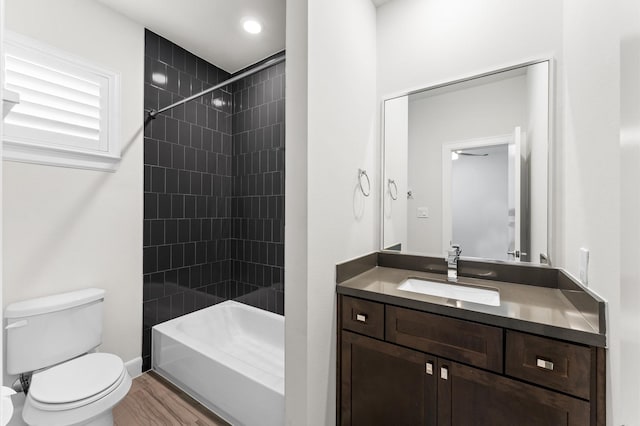 full bathroom with toilet, tiled shower / bath, wood finished floors, and vanity