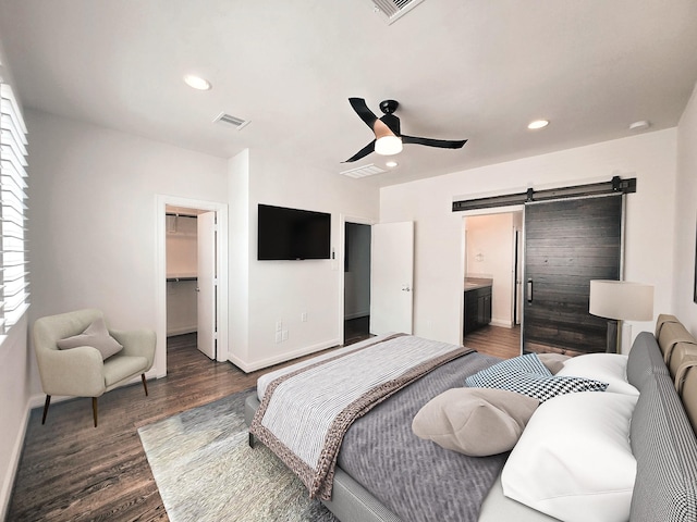 312 Eado Park Cir, Houston, TX 77020 - bedroom featuring a barn door, a walk in closet, dark wood-style floors, baseboards, and recessed lighting