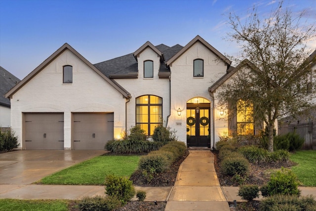 8818 Laurel Crest Dr, Missouri City, TX 77459 - french country style house with an attached garage, a shingled roof, driveway, and brick siding