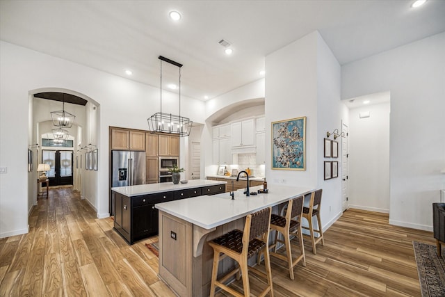 8818 Laurel Crest Dr, Missouri City, TX 77459 - kitchen with a large island with sink, light countertops, a breakfast bar, arched walkways, and appliances with stainless steel finishes
