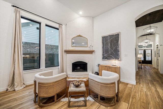 8818 Laurel Crest Dr, Missouri City, TX 77459 - sitting room with wood finished floors, an inviting chandelier, baseboards, lofted ceiling, and a brick fireplace