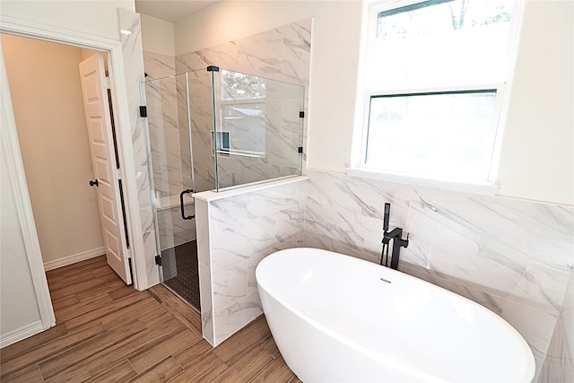 24994 Armagh St, Hempstead, TX 77445 - full bathroom featuring a soaking tub, a marble finish shower, wood finished floors, plenty of natural light, and tile walls