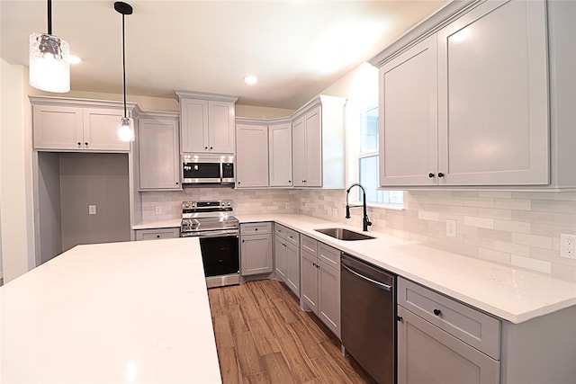 24994 Armagh St, Hempstead, TX 77445 - kitchen with stainless steel appliances, a sink, gray cabinets, decorative backsplash, and light wood-style floors