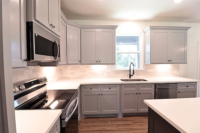 24994 Armagh St, Hempstead, TX 77445 - kitchen with stainless steel appliances, a sink, gray cabinets, tasteful backsplash, and dark wood-style flooring