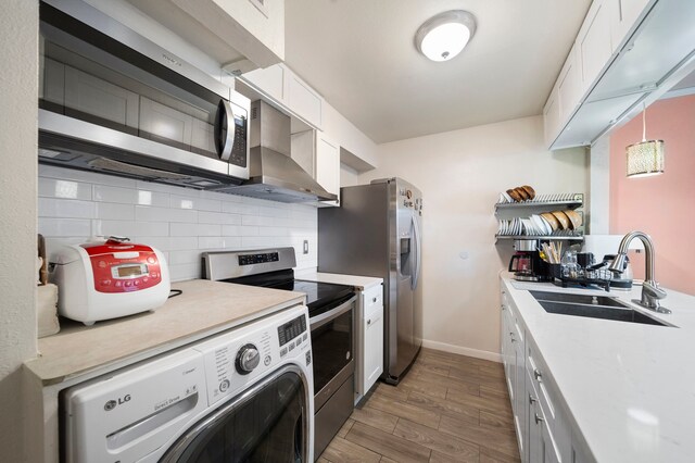 8931 Gaylord St Unit 161, Houston, TX 77024 - kitchen with a sink, washer / dryer, stainless steel appliances, white cabinets, and backsplash