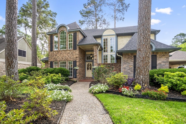view of front of property featuring brick siding and roof with shingles