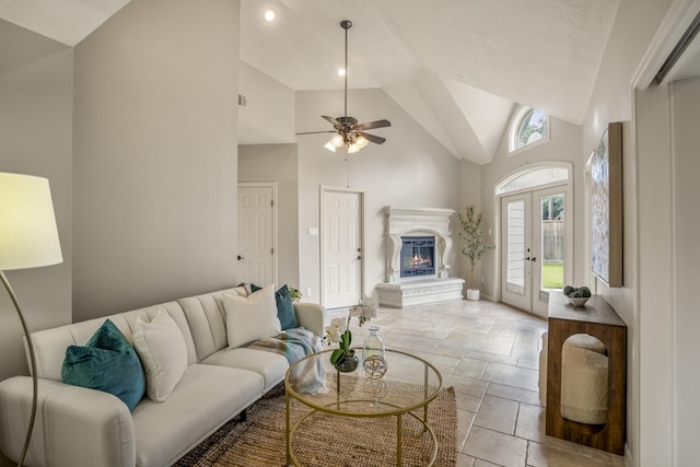 living room featuring a glass covered fireplace, high vaulted ceiling, ceiling fan, and baseboards