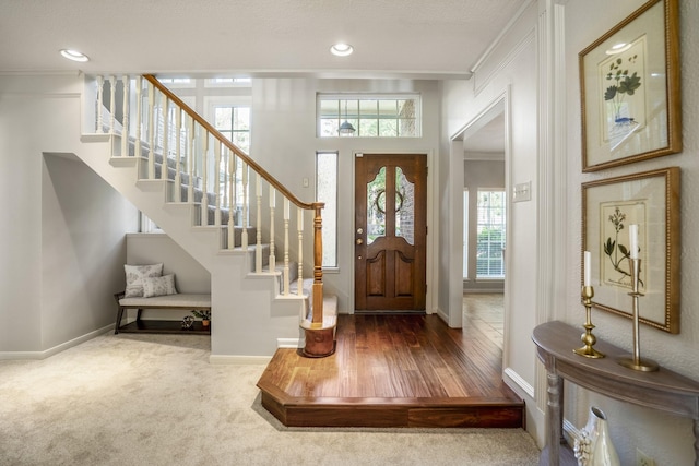 carpeted entryway featuring baseboards, ornamental molding, stairs, and recessed lighting