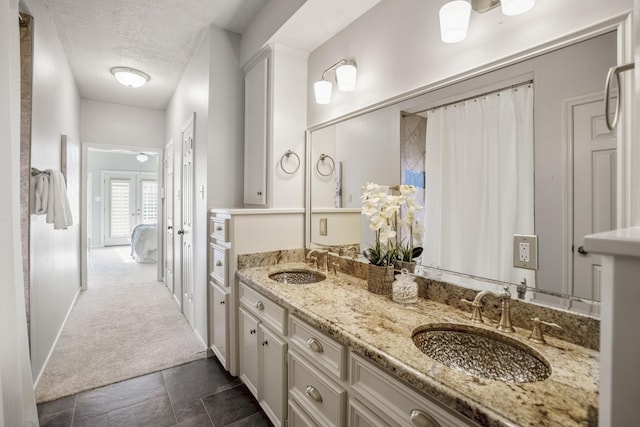 full bathroom featuring a sink, a textured ceiling, ensuite bathroom, and double vanity