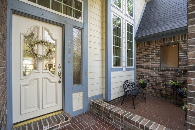 property entrance featuring a porch and a shingled roof